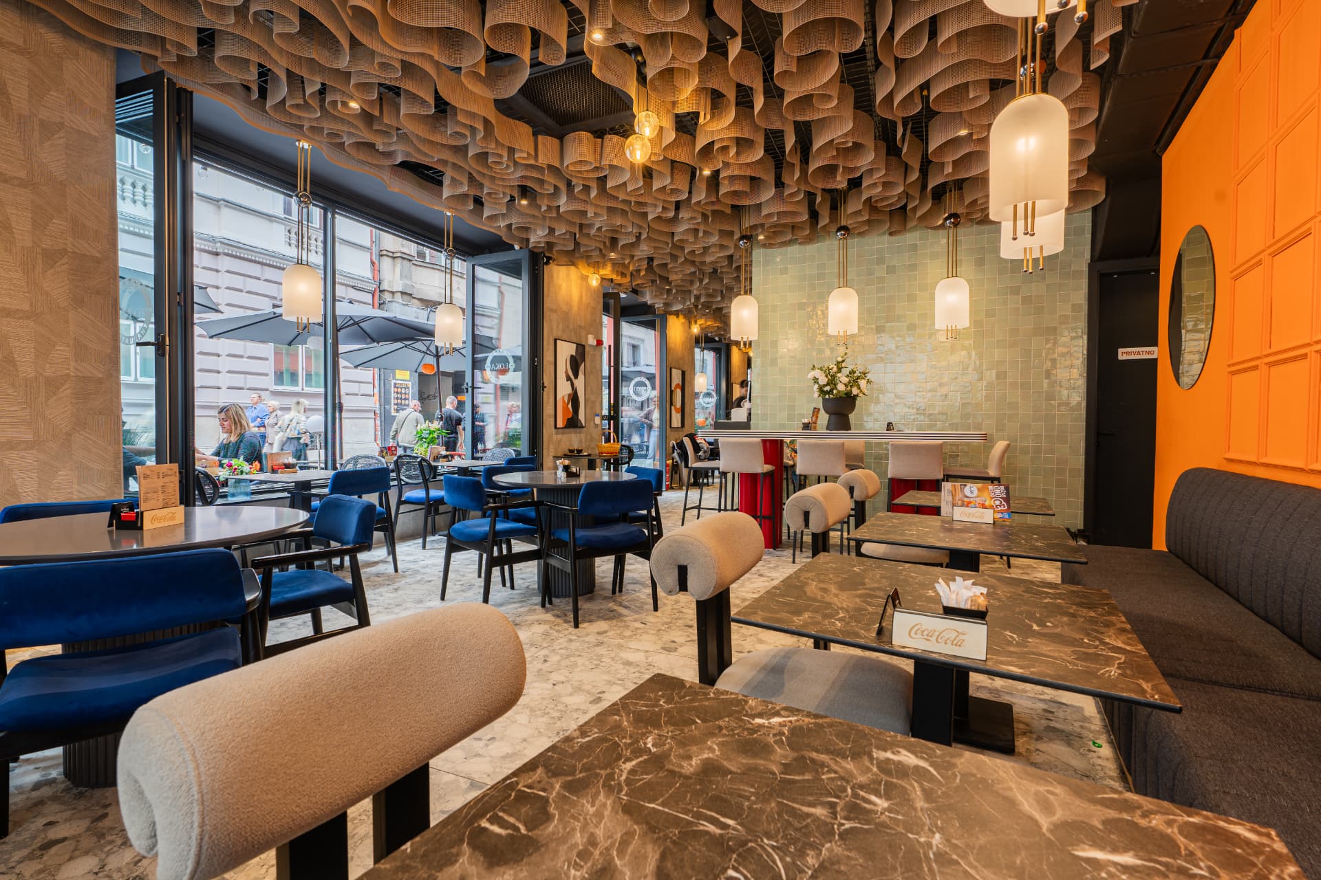 Enterijer restorana LOKA sa plavim baršunastim sjedištima i mramornim stolovima